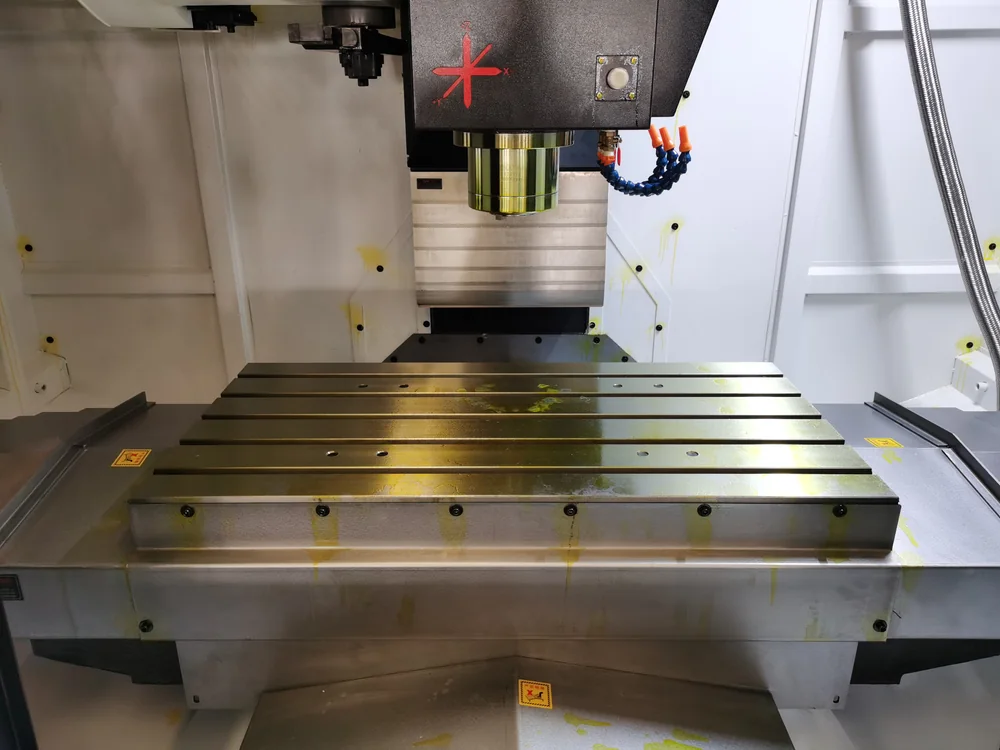 Vertical spindle above an empty T-slot table inside a machining center